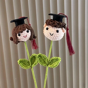 Detail of hand-crocheted graduation bouquet featuring boy and girl dolls with tassels