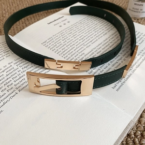 Detailed view of a dark green leather bow belt with golden buckle on an open book
