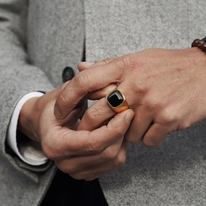 Men's gold signet ring with black square stone worn with a classic business suit