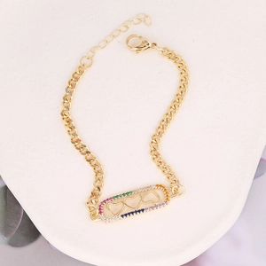 Detail of gold bracelet featuring rainbow zircon hearts on a hollow rectangular charm