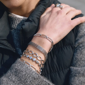 Silver stacked Cuban link bracelets with star charms and rhinestones on female wrist