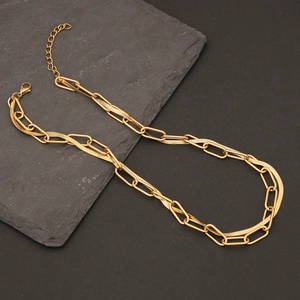 Dual-layered golden necklace featuring paperclip and snake chains on a dark stone background