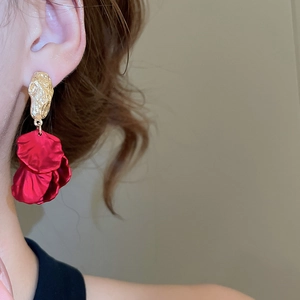 Close-up of model wearing red petal tassel drop earrings with gold textured metal studs