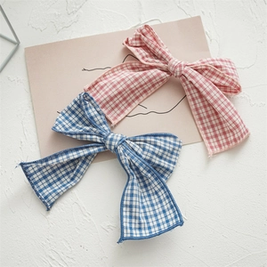Close-up of pink and blue plaid fabric bow hair clips on a textured background