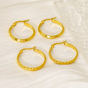 Detailed shot of gold twisted rope hoop earrings and Greek key pattern earrings