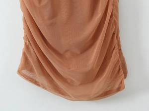 Détail du tissu en maille froncée marron clair sur une robe sans manches en tulle
