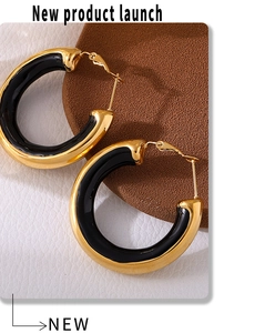 Detail view of bold gold and black enamel hoop earrings with a polished 18K gold finish