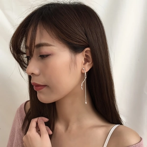Elegant silver S-curve wave earrings with tassels on a model with minimalist background