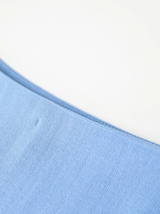 Detailed macro view of light blue denim knit fabric texture and high-quality stitching