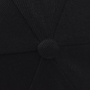 Gros plan sur le bouton supérieur et les coutures de cette casquette de baseball en coton noir