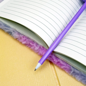 Gros plan d'un carnet en peluche violette avec pages lignées et stylo à bille assorti