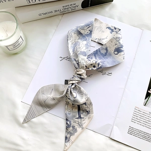 Elegant silk twilly scarf with ocean illustrations styled on books for a luxury lifestyle look