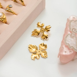 18K gold plated stainless steel floral earrings with white enamel finish on white pedestal