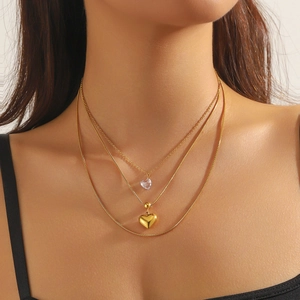 Layered gold-plated stainless steel snake chain necklace with heart pendants on model