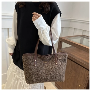 Detail of plush brown tote bag featuring leather shoulder straps and a gold brand logo