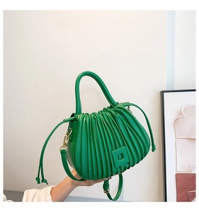 Detail view of emerald green pleated bucket bag with matte PU leather and gold hardware
