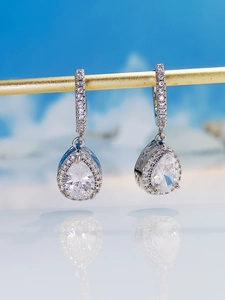 Macro shot of silver teardrop earrings with pear-cut crystals and halo pavé diamonds