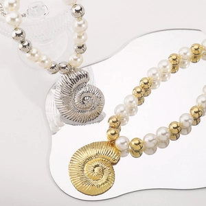 Detailed close-up of mixed gold and silver conch shell pendants on pearl necklaces