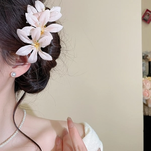 Detailed view of pink fabric flower hair pin with realistic dew drops on hair bun