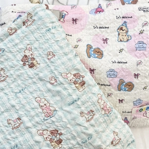 Detail of quilted cosmetic bag fabric featuring embossed cartoon patterns and logo label