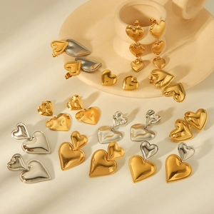 Golden and silver heart-shaped stainless steel earrings in various styles on a tray