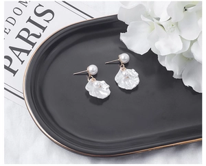 Vue détaillée de boucles d'oreilles fleur en nacre et perles sur un plateau noir