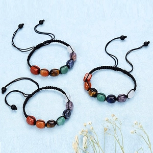 Adjustable 7 chakra braided bracelets with natural raw stones on a blue background