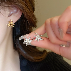 Detailed comparison of gold and silver flower stud earrings held for scale and size