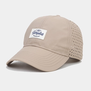 Detail of breathable laser-cut holes and Baradise fish patch on light beige baseball cap