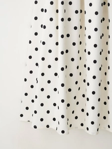 Gros plan du tissu blanc à pois noirs de la robe bustier avec texture fine