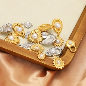 Stainless steel heart and sun pendants with pearls on champagne silk and wood background