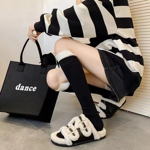 Fashionable black and white fleece platform sandals styled with knee-high socks and tote