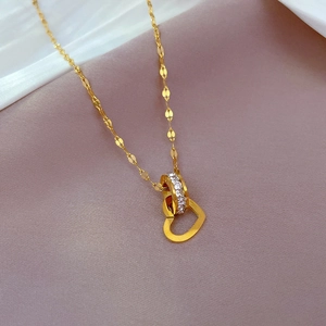 Detailed macro view of gold heart pendant and zircon circle on a woven steel chain
