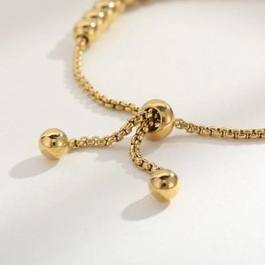 Vue macro du fermoir coulissant doré réglable sur un bracelet en perles d'acier inoxydable