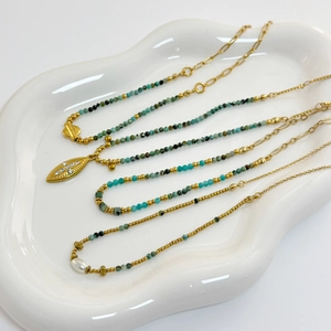 Detail of African pine stone necklace with leaf pendant and pearls on white tray