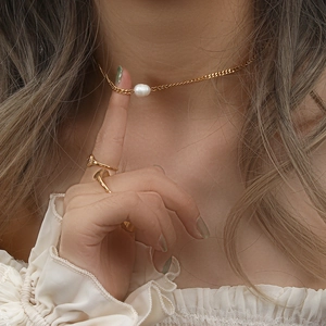 Detail of gold Cuban link necklace with freshwater pearl pendant on female model