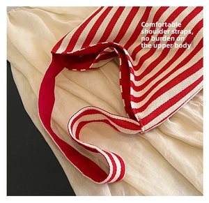 Detail view of red and white striped canvas tote bag straps on a textured fabric surface