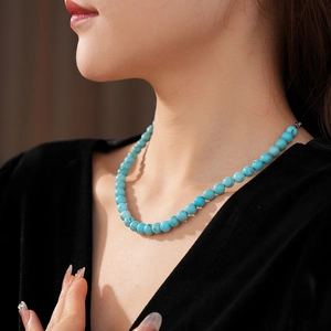 Detail of elegant turquoise beaded necklace on model with black velvet dress