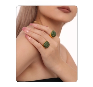 Macro detail of 18K gold plated titanium rings with green zircon stones on model fingers
