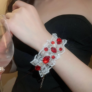 Détail d'un bracelet en dentelle blanche avec pierres rouges et chaîne réglable en métal