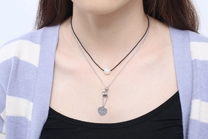 Detail of a layered necklace with white pearl and heart pendant engraved with Love