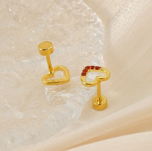Detailed macro view of gold heart earrings with red crystals on champagne silk background