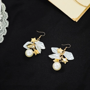 Detail of French vintage earrings with white petals, pearls, and gold stars on black lace