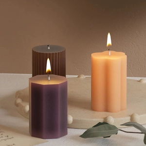 Three textured geometric scented candles in brown, purple and orange on a stone tray