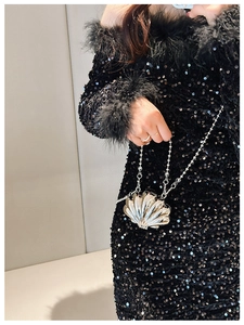 Silver metal lip-shaped mini clutch with chain strap carried by a model in black dress
