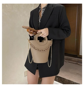 Khaki bucket bag with gold chain strap and ring handle shown on a model