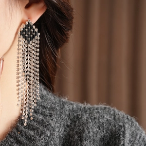 Close-up of diamond rhombus tassel earrings on model with sparkling zircon details