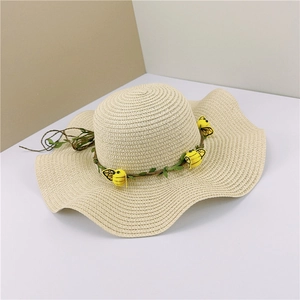 Détail d'un chapeau de paille ondulé avec bande de vigne décorative et petites abeilles jaunes