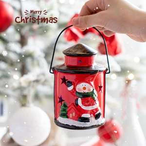 Red metal Christmas lantern with Santa Claus pattern and star cutouts in snowy scene