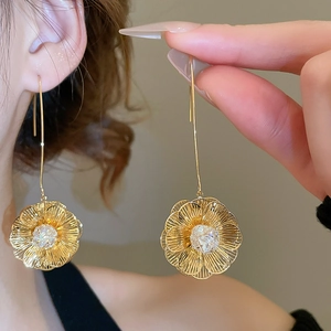 Gros plan de boucles d'oreilles longues dorées 18K avec pendentifs fleurs évidés et zircon